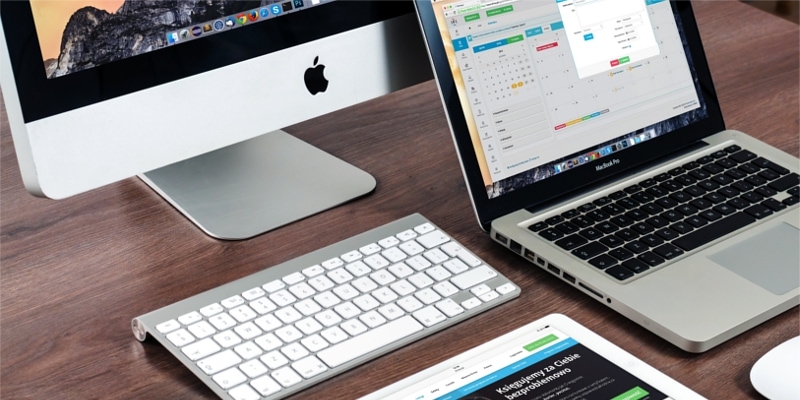 Mac Pc With Keyboard Laptop Mouse And Tablet Against Dark Wood Desk