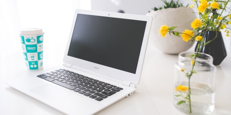 Blogging Laptop With Blue Plastic Drink Cup And Yellow Flowers