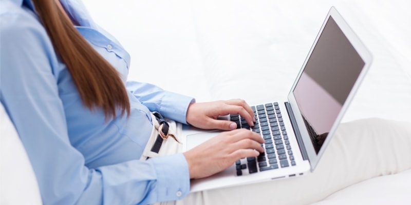 Female Blogger In Blue Shirt Typing On Laptop