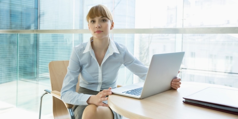 Female Blogger Using Laptop On Desk In An Office