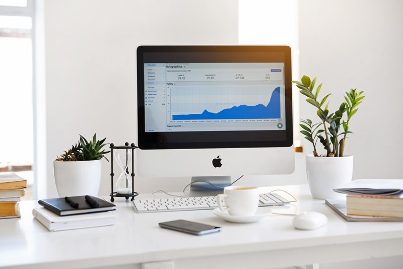 How To Use Pinterest For Business Header Image Of Mac On White Desk With Plants & Notebooks