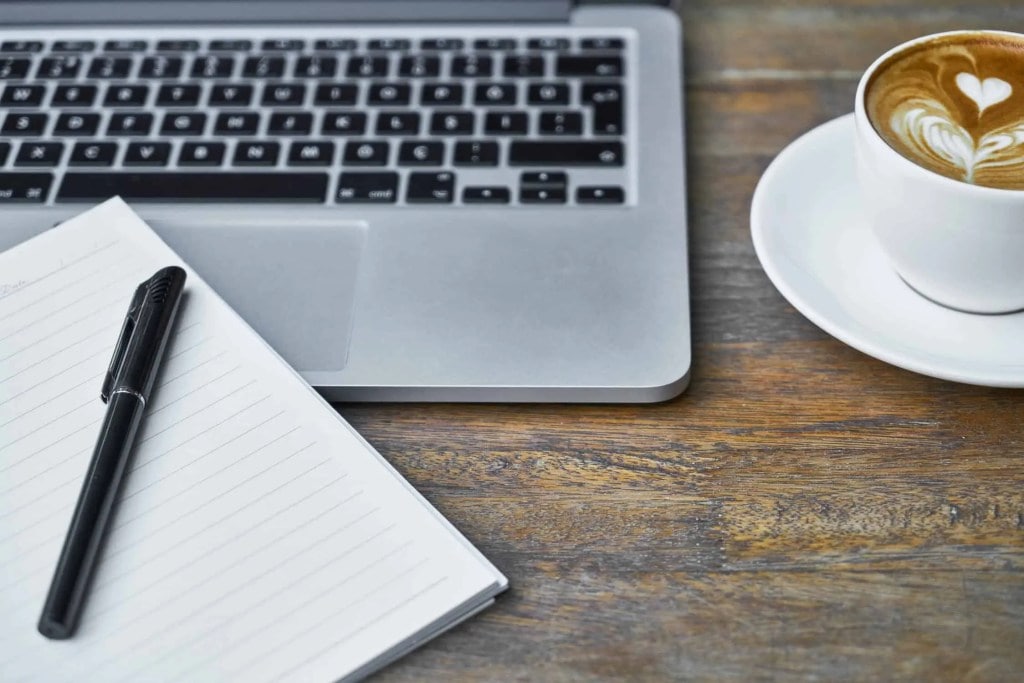 Hidden WordPress Gutenberg Features Header Image Of Notepad Coffee Cup And Laptop On Dark Wood